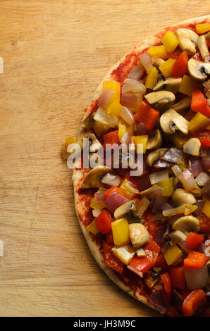 Overhead shot of pizza at the pre-baked stage.  Topped with fried or sauteed mixed vegetables and no cheese. Stock Photo