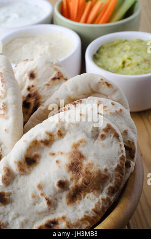 Table laid with a fresh vegetarian buffet of pitta breads and a selection of dips, with crudites in small bowls. Stock Photo