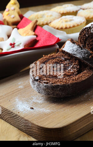 A sweet Christmas dessert buffet on wooden table, with chocolate yule log, shaped biscuits and mince pies in background. Stock Photo