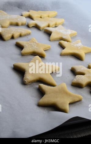 A selection of pastry cut outs from biscuit or cookie dough on a baking tray covered in parchment paper, ready to be baked in oven. Stock Photo