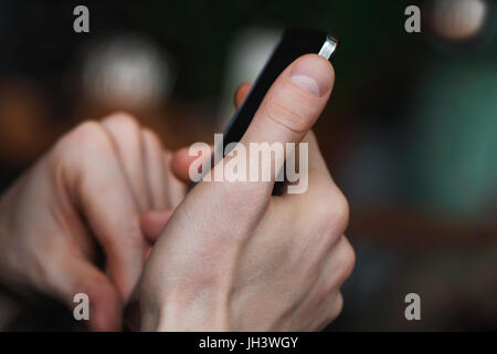 Close-up of mans hands holding smartphone. Blurred background. Stock Photo
