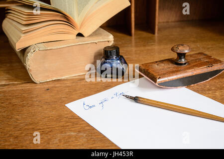 Phrase “Once upon a time” written in ink, on paper sheet surrounded with a fountain pen, an ink pot, a blotting paper holder and with old books. Stock Photo