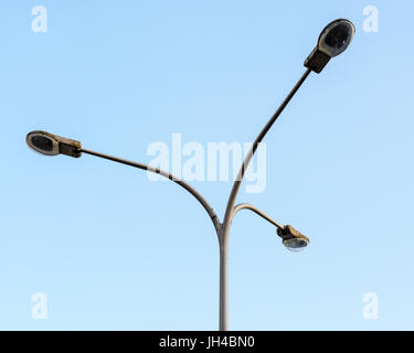 Vintage street light pole with three lamps against blue sky. Stock Photo
