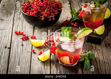 Ideas of summer drinks, dietary healthy cocktails. Mojito from lime, mint and red currant. On the old rustic wooden table, with the ingredients. Copy 