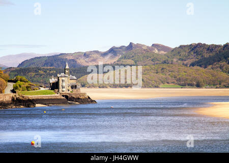 Old gothic building on estuary in Barmouth, North Wales. Blue water and golden sand with rugged welsh mountains in the background. Stock Photo