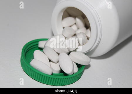 White pills spilling from bottle Stock Photo