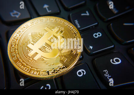 Golden bitcoin coin on the black laptop keyboard. Stock Photo