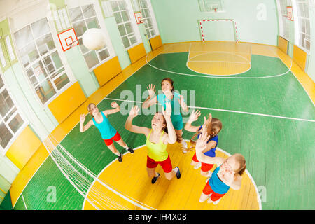 Top view portrait of teenage girls, volleyball players, catching the ball during the game in sports hall Stock Photo