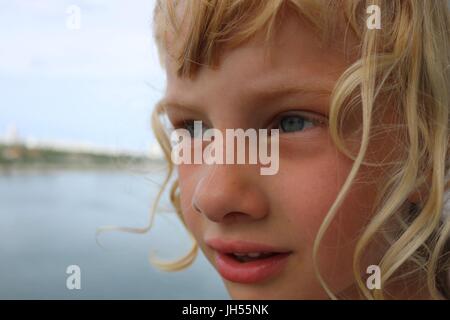 Close up portrait of young blonde girl staring at ocean Stock Photo