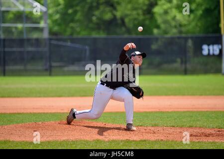 Pitcher delivering a pitch to an opposing hitter during a high school baseball game. USA. Stock Photo