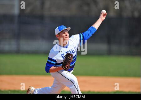 Pitcher delivering a pitch to an opposing hitter during a high school baseball game. USA. Stock Photo