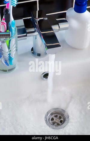 Modern water tap, water in the sink and  hygiene objects. Bathroom scene