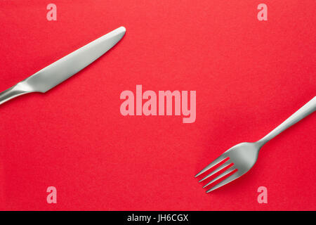 Fork and knife on red. Food theme template and background Stock Photo