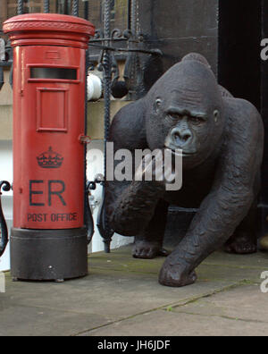 gpo post office postman red pillar box and monkey or gorilla concept shot comment on the royal mail staff and management Stock Photo