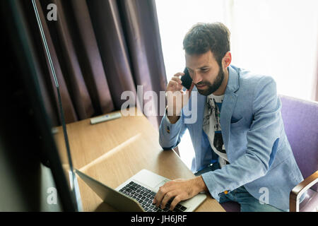Portrait of successful young handsome man using laptop Stock Photo