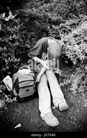 A longtime 'maintainance' drug addict, 'Joe' shoots up with about $3.00 worth of heroin while hiding in the bushes under an urban highway bridge. Stock Photo