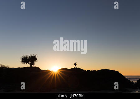 A walking hiker is silhouetted on a ridge line by a beautiful bright sunrise in Australia. Stock Photo