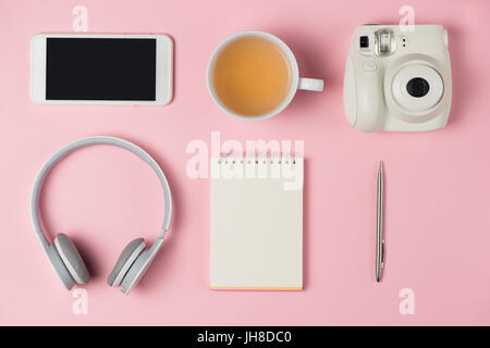 Top view of working desk with blank notebook with pen, tea cup, mobile phone and camera on wooden background Stock Photo