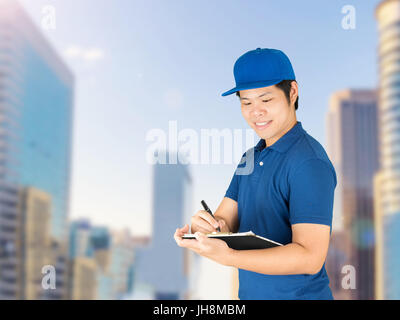 asian delivery man writing on notepad Stock Photo