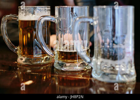 Three pitchers with a different amount of beer in them Stock Photo