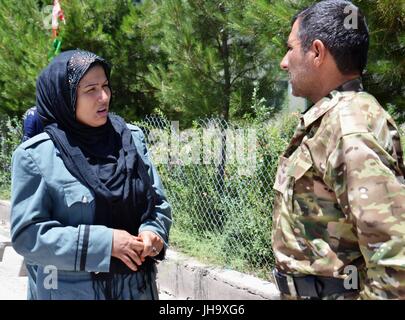 Tirin Kot, Afghanistan. 13th July, 2017. Afghan policewoman Masouma (L) speaks with a colleague at the workplace in Tirin Kot, Uruzgan province, Afghanistan, July 7, 2017. In conservative Afghan society, people particularly in the countryside regard women working outside of their family home as a 'taboo.' But one brave female, Masouma, 45, has escaped the cultural barriers and joined the police force to break the taboo and show that women can compete with men in all arenas. Stock Photo