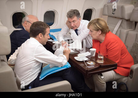 HANDOUT - Handout picture made available on 12 July 2017 showing German Chancellor Angela Merkel and French President Emmanuel Macron conversing on the way to Paris from the West Balkans Conference in Trieste aboard an Airbus of the German Armed Forces, along with their advisors Christoph Heusgen and Philippe Etienne (covered). ATTENTION EDITORS: EDITORIAL USE ONLY IN CONNECTION WITH CURRENT REPORTING / MANDATORY CREDITS) Photo: Guido Bergmann/Bundesregierung/dpa Stock Photo