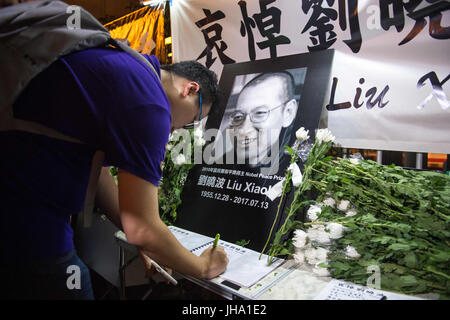 Hong Kong, Hong Kong SAR, China. 13th July, 2017. People gather to leave flowers and sign the condolence book. Following the death in China of Liu Xiaobo, the Nobel peace laureate, people protest outside the Liaison Office of the Central People's Government in the Hong Kong Special Administrative Region. Credit: Jayne Russell/ZUMA Wire/Alamy Live News Stock Photo
