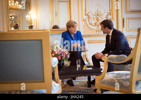 dpatop - HANDOUT - Handout picture made available on 13 July 2017 showing German Chancellor Angela Merkel and French President Emmanuel Macron conversing at the start of the Franco-German Council of Ministers in the Élysée Palace in Paris, France. (ATTENTION EDITORS: EDITORIAL USE ONLY IN CONNECTION WITH CURRENT REPORTING / MANDATORY CREDITS) Photo: Guido Bergmann/Bundesregierung/dpa Stock Photo