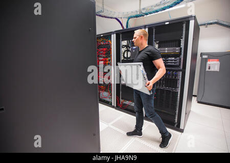 Full length of male IT engineer carrying blade server while walking in datacenter Stock Photo