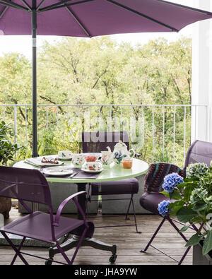 Purple chairs and parasol by table on deck Stock Photo