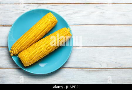 boiled corn on blue plate on white wooden background Stock Photo