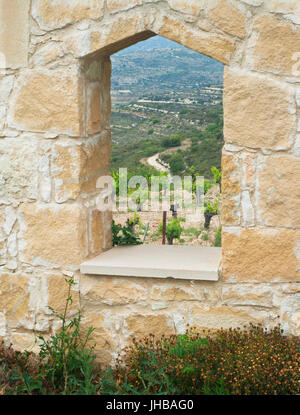 view of cypriot mountain vineyard through hole in stone wall Stock Photo