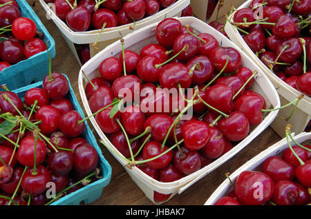 Cherries displayed in baskets for market on wooden table Stock Photo