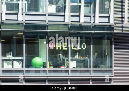 Office worker spells out 'hello' with sticky notes on window, London, UK Stock Photo