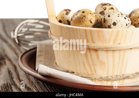 Quail eggs in a wooden bucket on a wooden table Stock Photo