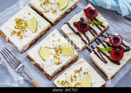 Raw pistachio, coconut, lime and chocolate-cherry cheesecakes. Love for a healthy vegan food concept. Stock Photo
