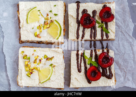 Raw pistachio, coconut, lime and chocolate-cherry cheesecakes. Love for a healthy vegan food concept. Stock Photo