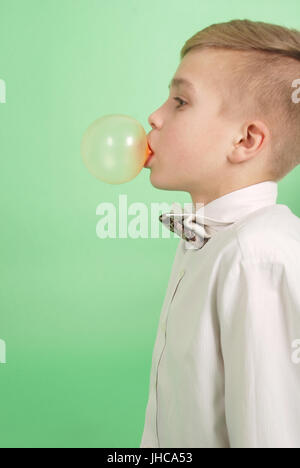 Boy blowing a bubblegum bubble isolated on green Stock Photo