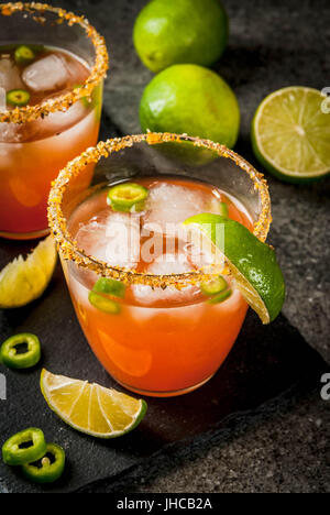 Alcohol. Traditional Mexican South American cocktail. Spicy michelada with hot jalapeno peppers and lime. On a dark stone table. Copy space Stock Photo