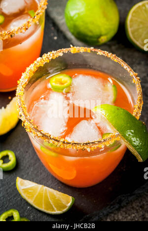 Alcohol. Traditional Mexican South American cocktail. Spicy michelada with hot jalapeno peppers and lime. On a dark stone table. Copy space Stock Photo