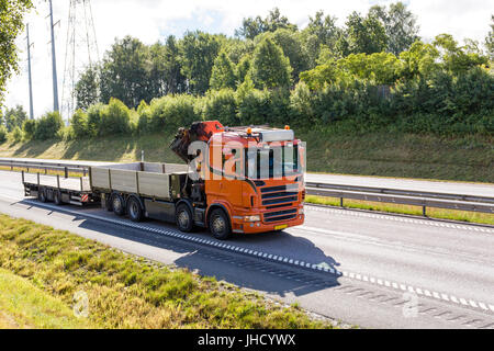 Orange truck / lorry with inbuilt cargo crane and trailer on motorway / highway / freeway  Model Release: No.  Property Release: No.  Note: All logos etc. removed. Stock Photo