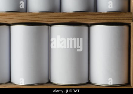 Rows of tin cans with unbranded, blank white labels, on wooden shelves. Stock Photo