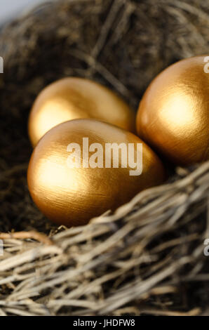 Close up of three gold painted eggs in a bird's nest. Stock Photo