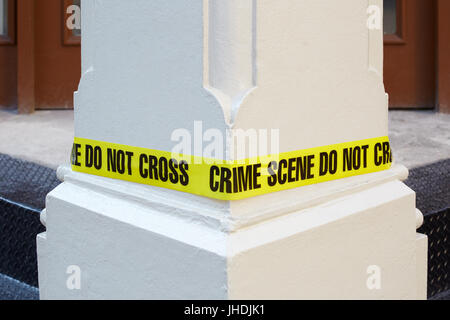Crime scene do not cross, yellow police tape around a white column Stock Photo