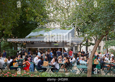 Shake Shack restaurant in Madison Square Park with people sitting, outdoor tables in New York