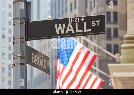 Wall Street sign near Stock Exchange with US flags, financial district in New York in a sunny day Stock Photo