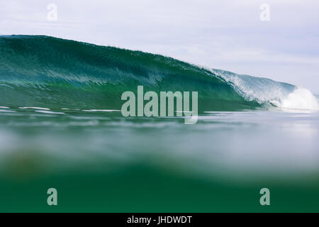 A water angle of an emerald wave breaking and barrelling at a surf break in Australia. Stock Photo