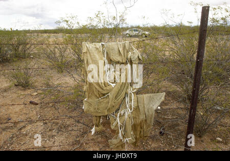 Discarded makeshift backpacks, commonly used by marijuana smugglers entering the United States from Mexico, hang on a fence near Santa Rita Road, Sonoran Desert, Sahuarita, Arizona, USA. Stock Photo