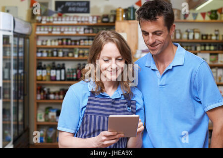 Male And Female Workers In Delicatessen Store Using Digital Tablet Stock Photo