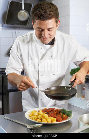 Chef Adding Sauce To Dish In Restaurant Kitchen Stock Photo